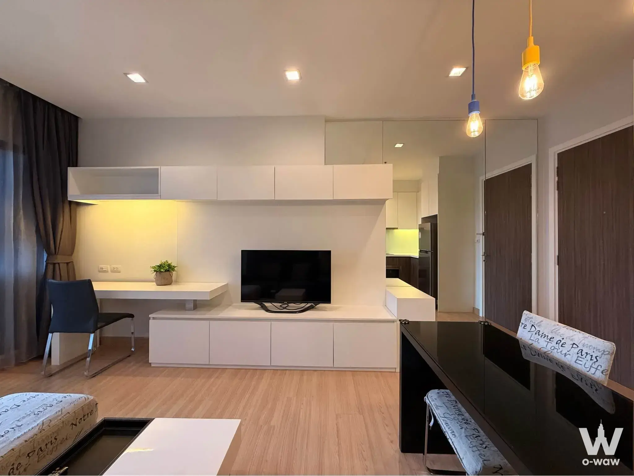 The living room in a 1-bed Urbano Absolute Sathon-Taksin condo for rent has a glossy white built-in unit and black TV