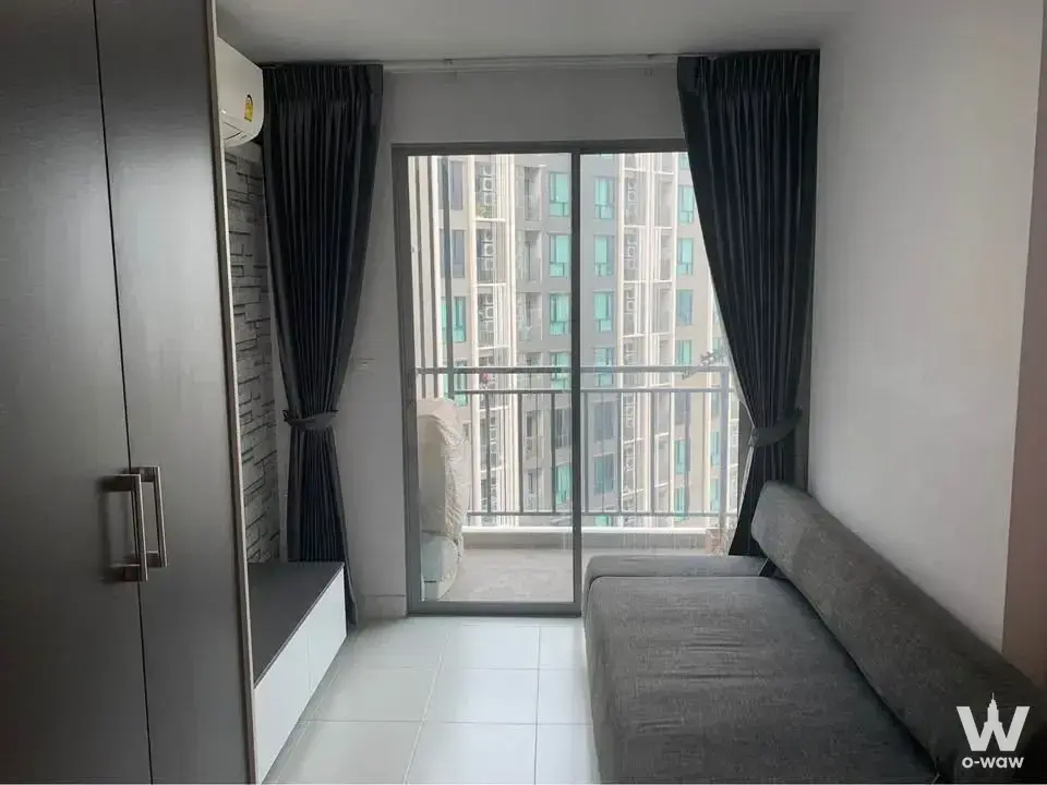 Studio living area with grey sofa and balcony access in Silk Place Phaholyothin Laksi