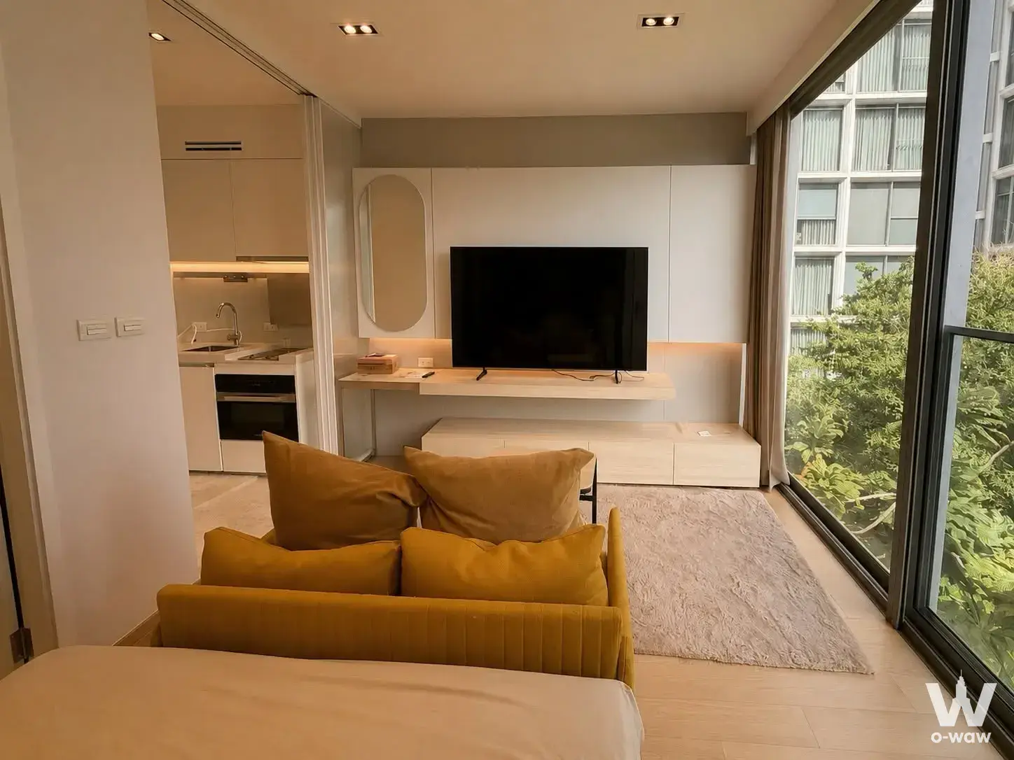 Mustard velvet sofa and built-in media wall in a studio condo for rent at SCOPE Promsri