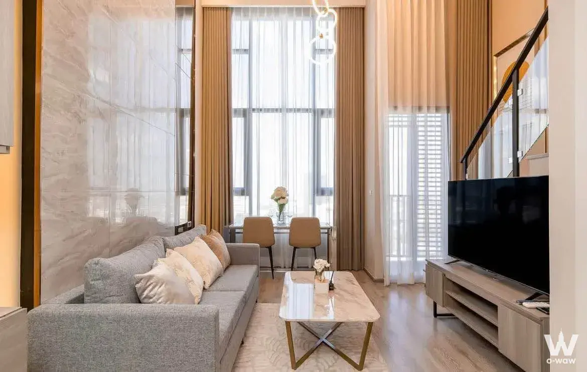 Modern 1-bed Knightsbridge Kaset Society living room featuring marble TV wall, gold accents, and natural light