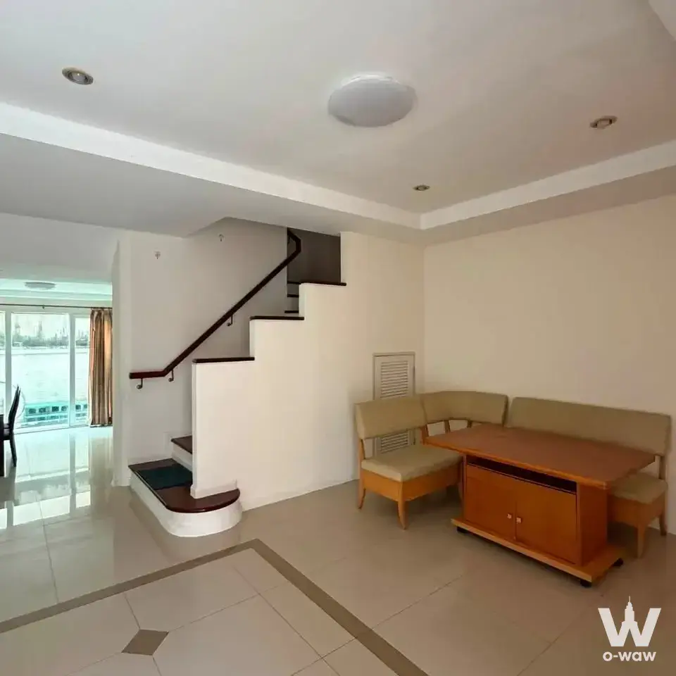 Living and dining area in 4-bed townhouse for rent at Supalai Parkville Ram Inthra 23 with staircase and river view