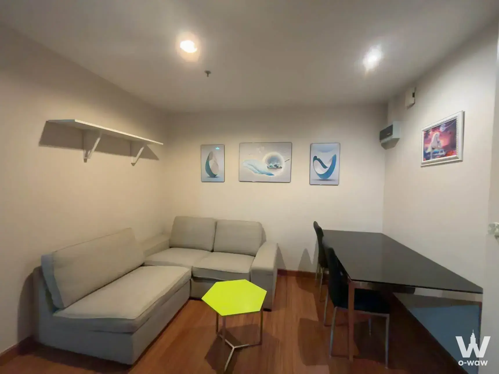 Furnished living-dining area in Diamond Ratchada Condominium with L-shaped sofa and yellow table