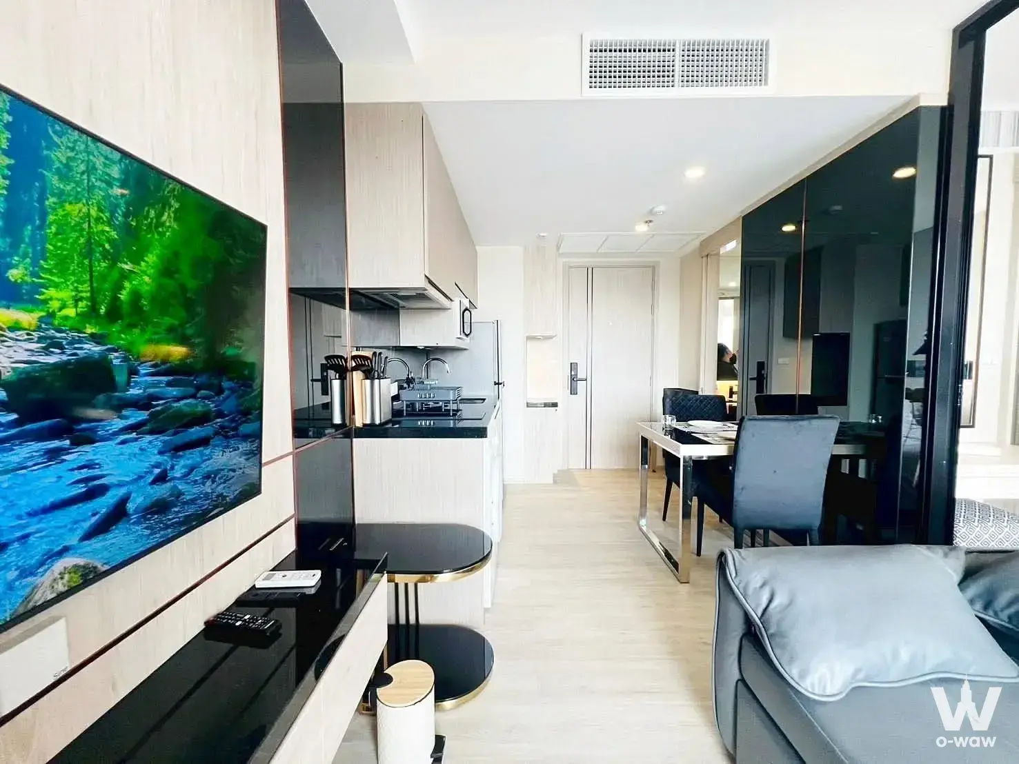 Luxury 1-bed condo living space in The Panora Pattaya with wood paneling and velvet dining chairs