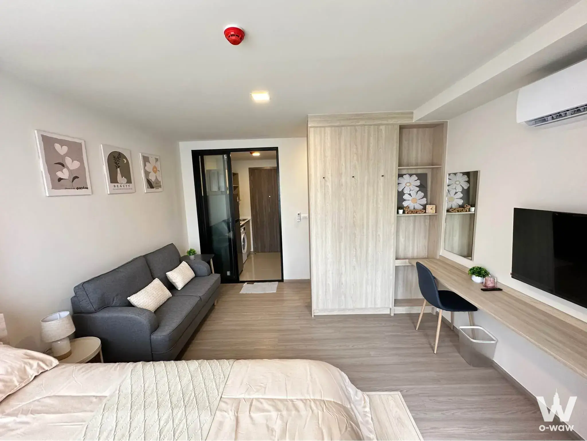 Furnished bedroom in THE MUVE Sukhumvit 107 with a queen bed grey sofa and light wood flooring