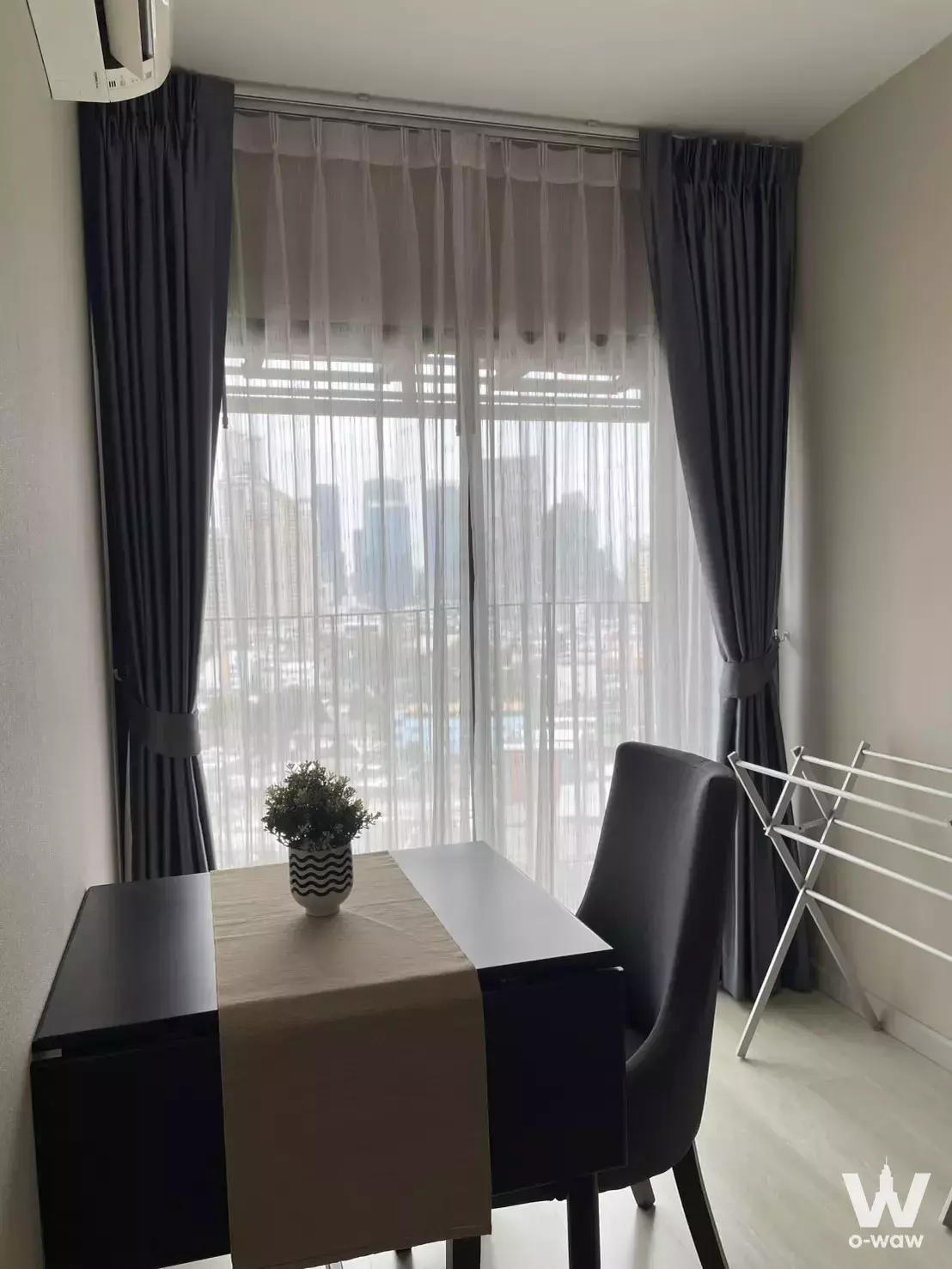 Bright home office nook with a dark wood desk and city skyline view through floor-to-ceiling windows at KnightsBridge Prime