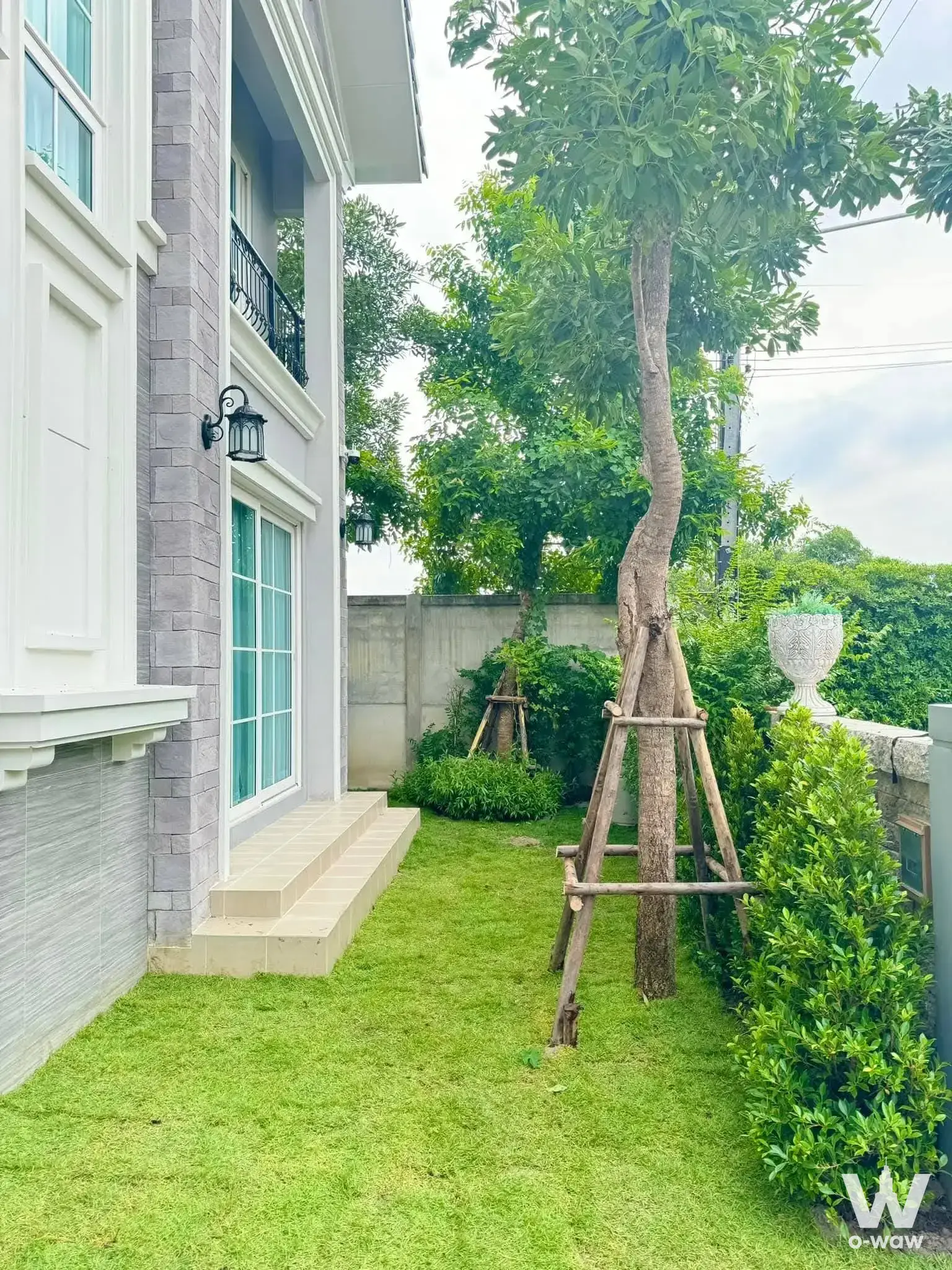 Grey brick exterior side yard with manicured lawn and sliding door at Prestige Future-Rangsit 4-bed villa