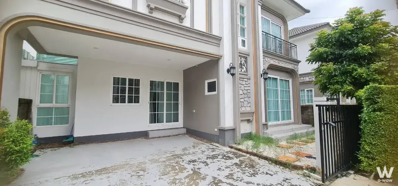 4-bed house for rent in Grandio Bangna KM.5 has white stucco exterior, arched carport and black metal gate