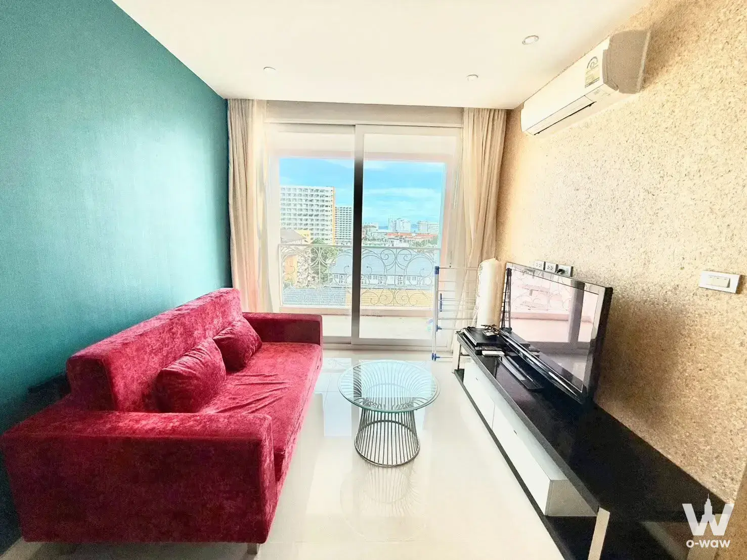 Living room in Grande Caribbean Condo featuring red velvet sofa and glass balcony door