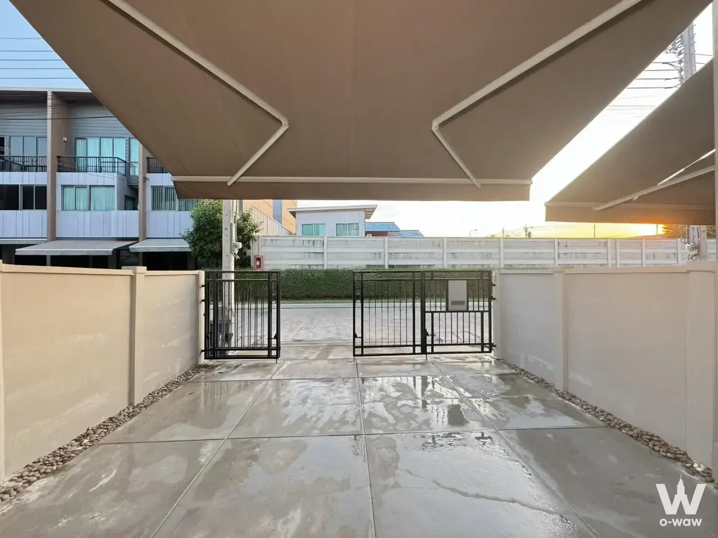 Covered driveway entrance with black metal gate and beige awning at Baan Klang Muang Rama 9 townhouse