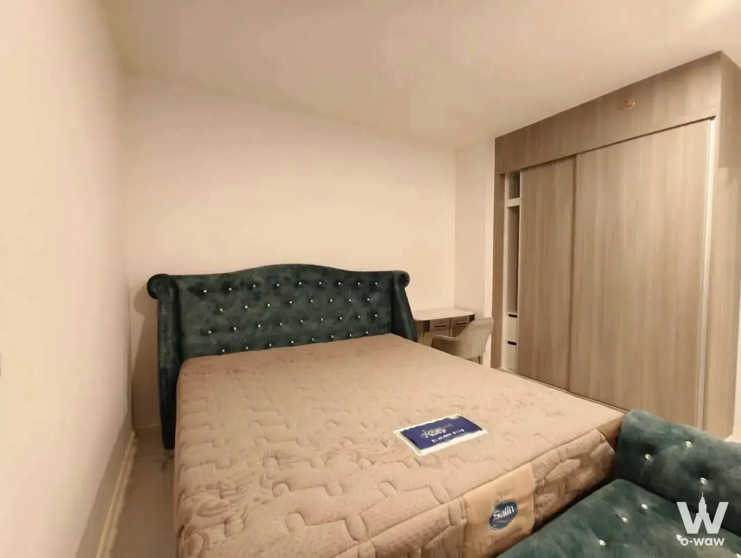 A Space Mega 1 small condo bedroom with dark green velvet headboard