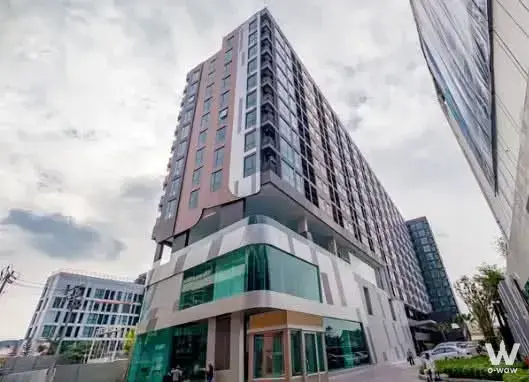 Salmon-pink high-rise exterior with glass curtain wall and commercial podium entrance in a 1-bed condo for sale at Rich Park
