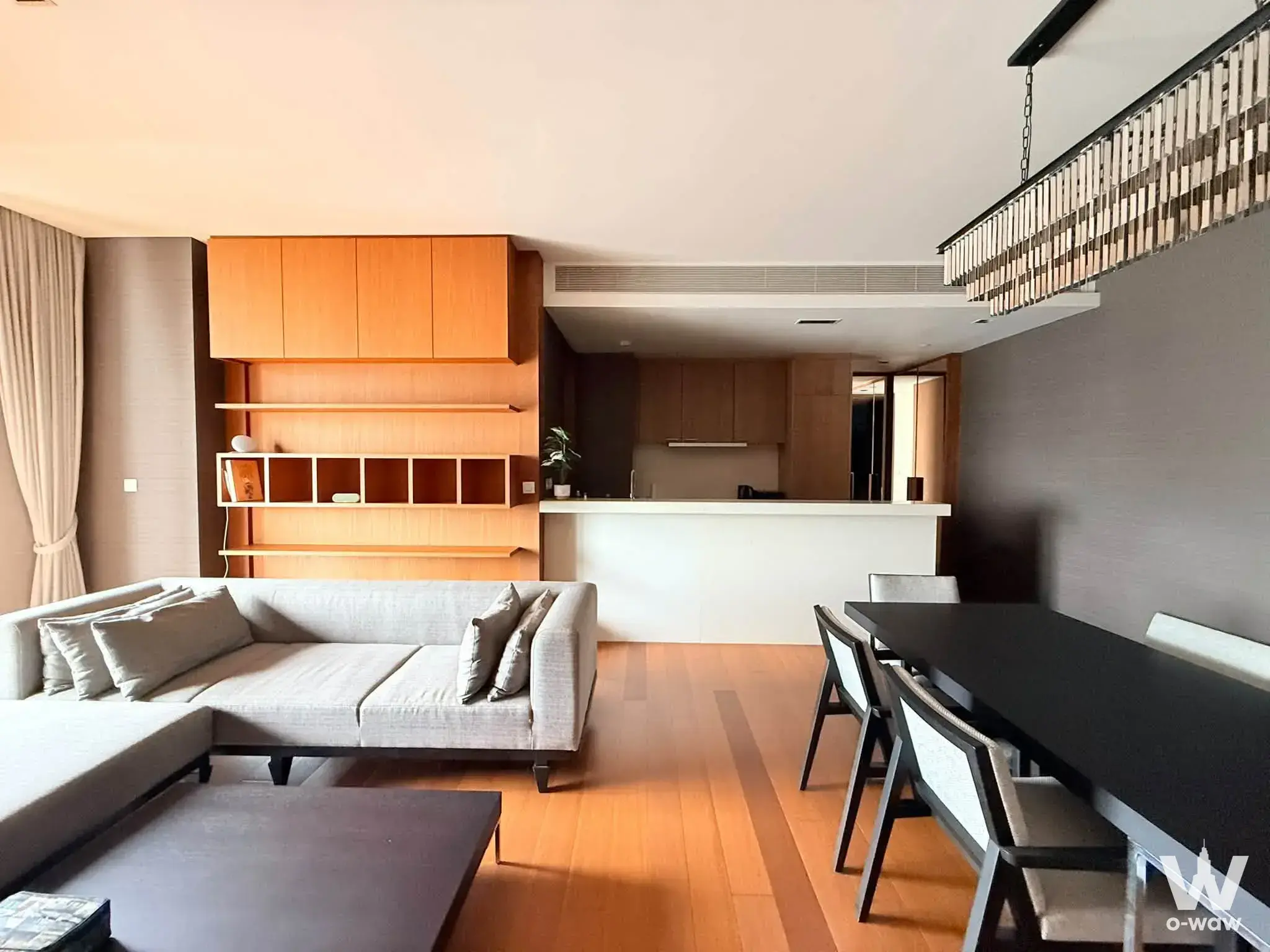 Modern 2-bed condo for sale in The Sukhothai Residences features an open-plan living area with a grey sectional sofa and