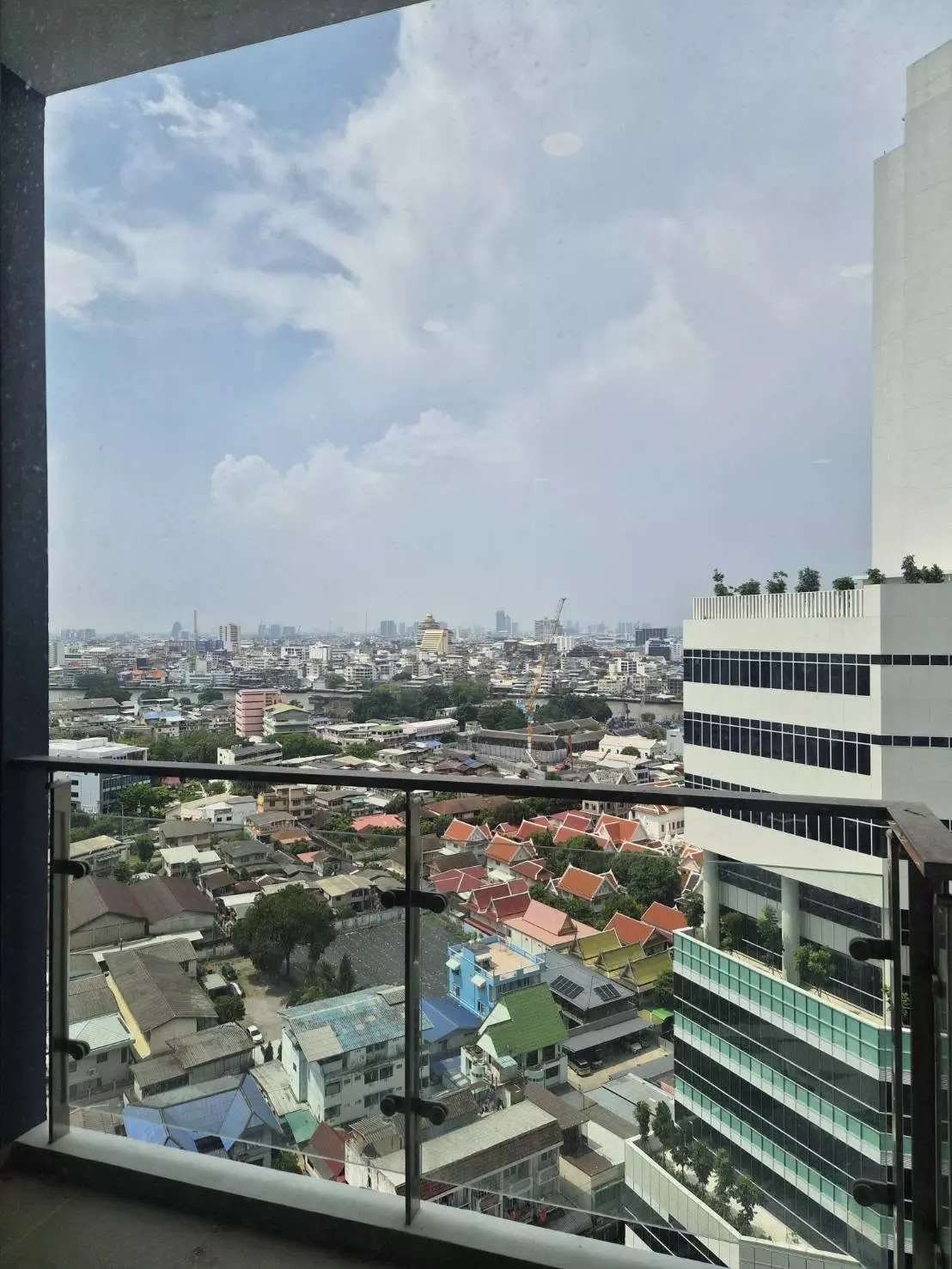 High-floor balcony at Supalai Premier Charoen Nakhon offering a panoramic city view with a golden temple spire