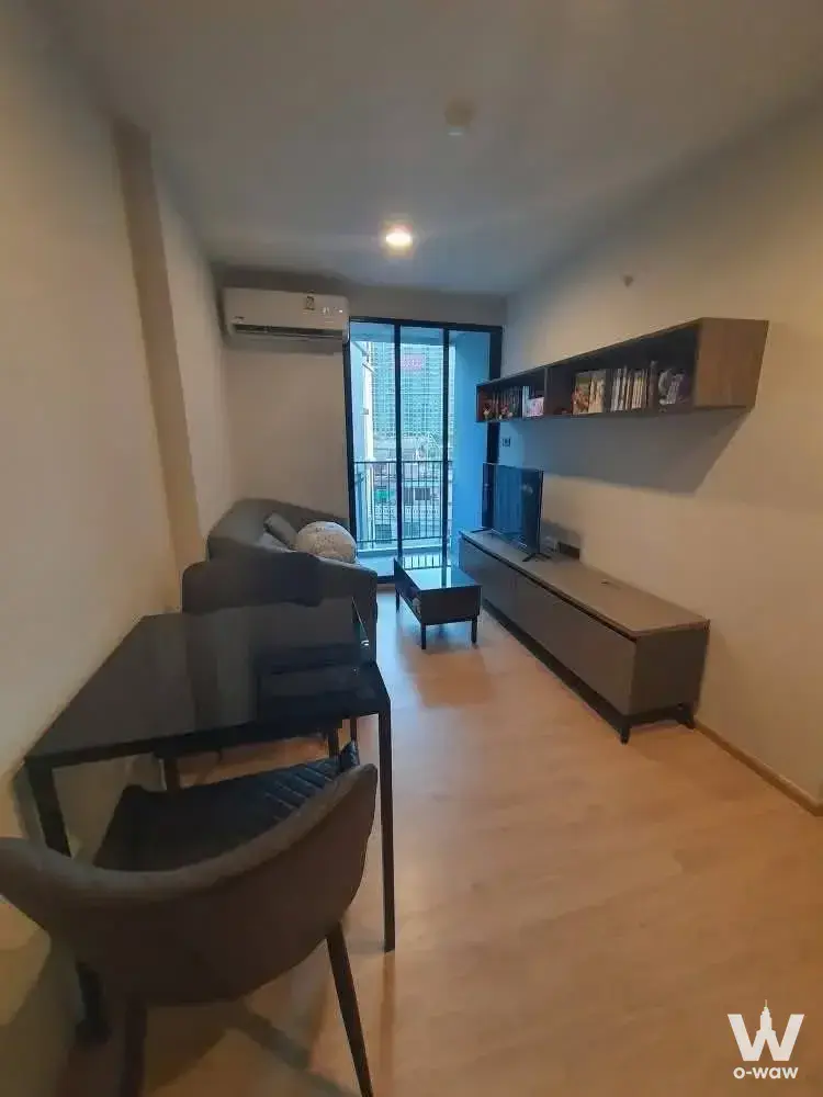 Bright living room in Premio Quinto condo with grey sofa and floor-to-ceiling balcony doors