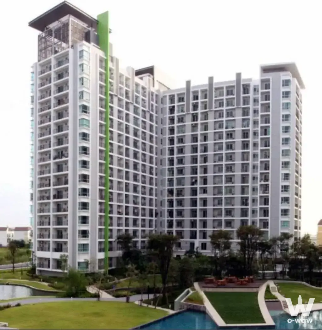 The Parkland Srinakarin Lakeside exterior showcasing white facade, green accent stripe, pool, and manicured grounds