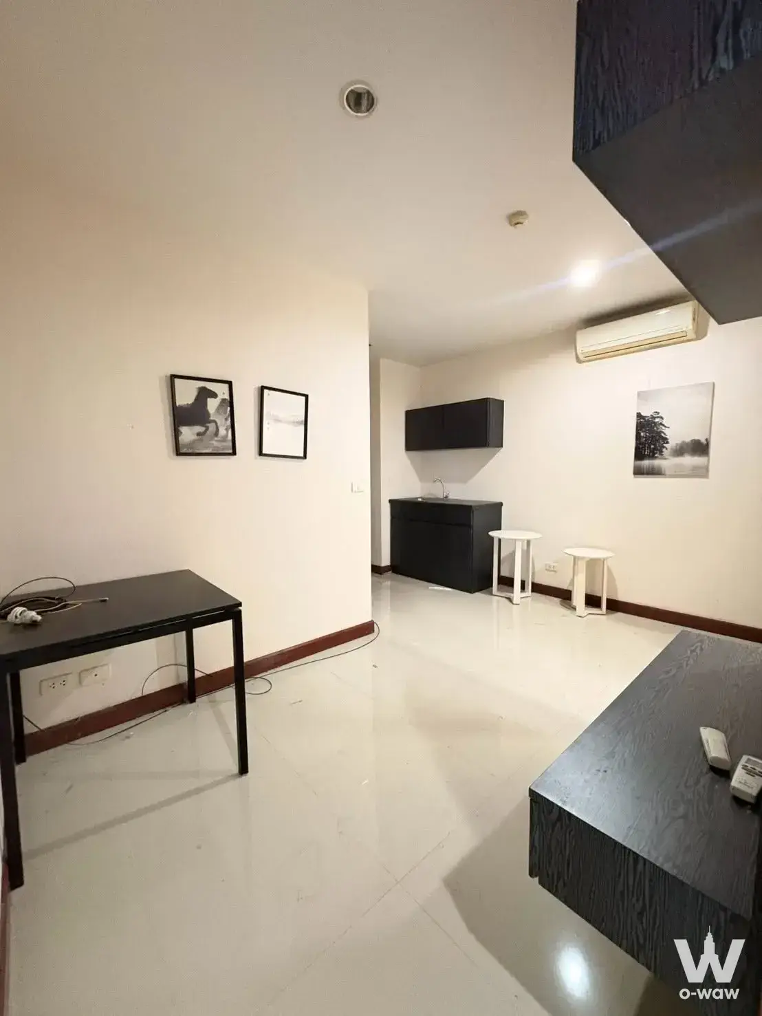 Tidy studio unit in Ease Ratchada Condo featuring black wood-grain kitchenette and minimalist decor