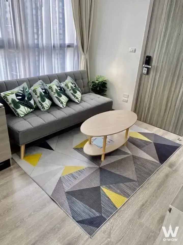 Furnished living room with grey sofa and tropical pillows in KnightsBridge Prime Onnut 1-bed condo for sale