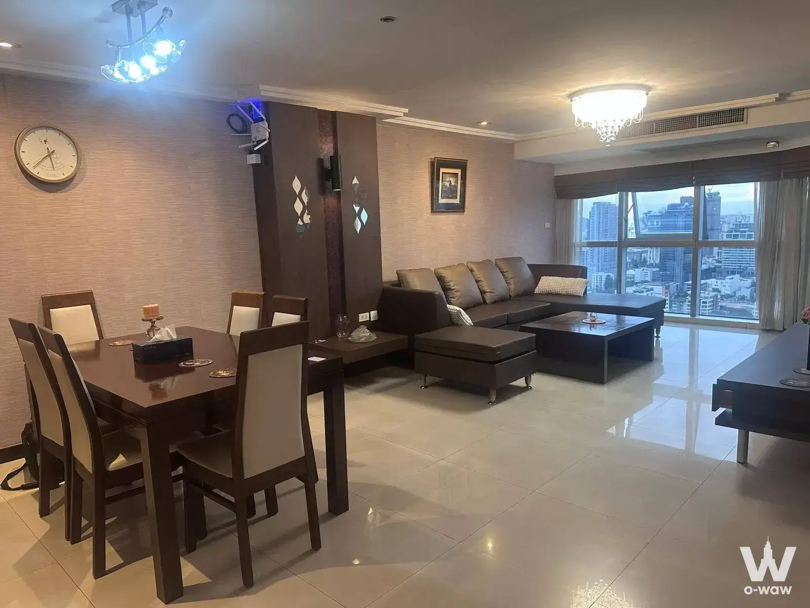 Open-plan living and dining room in Diamond Sukhumvit condo with leather sofa, wood accents, and city views