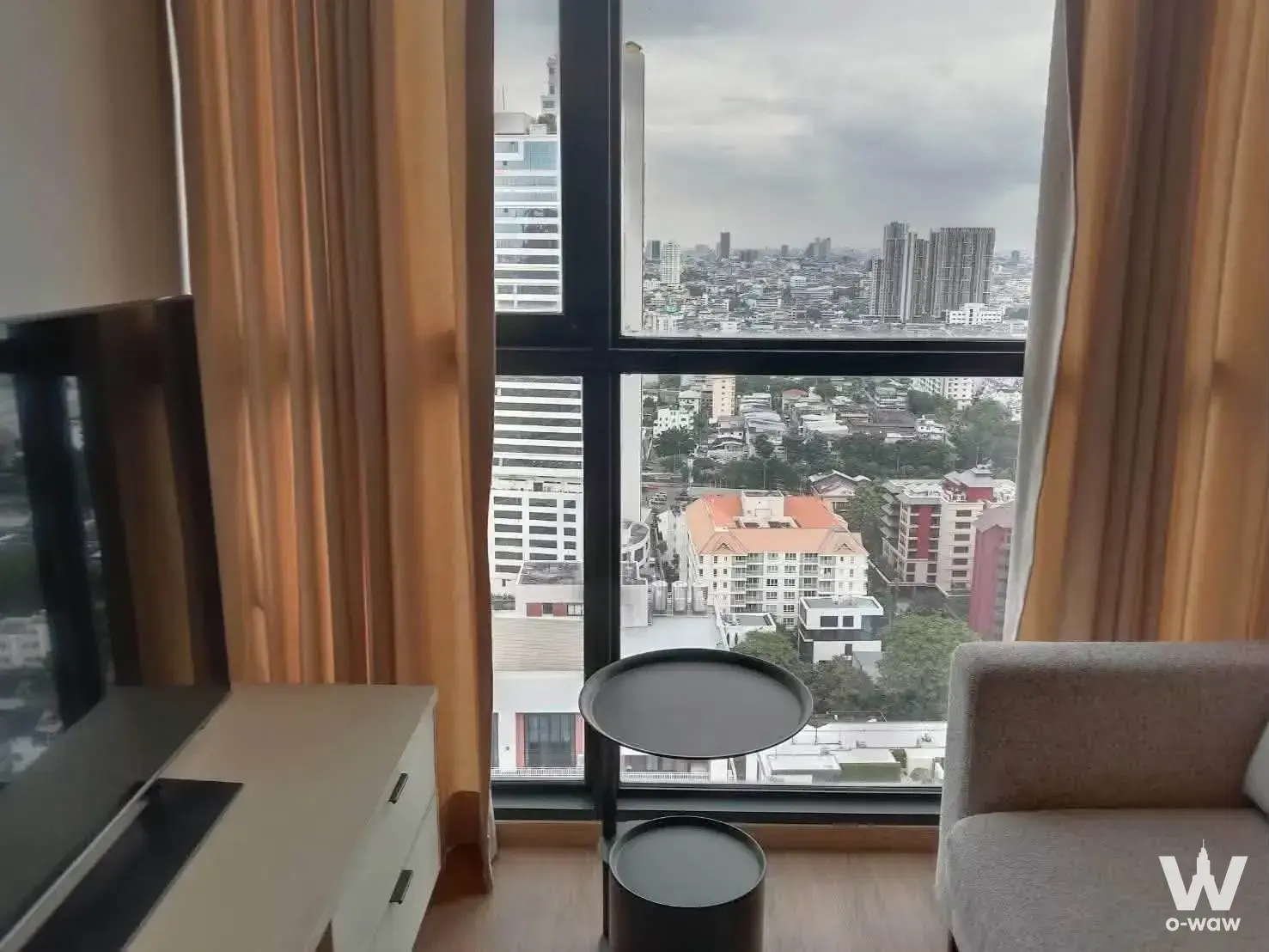 1-bed other for rent in The Issara Sathorn offers city skyline views through large black-framed windows in a modern living