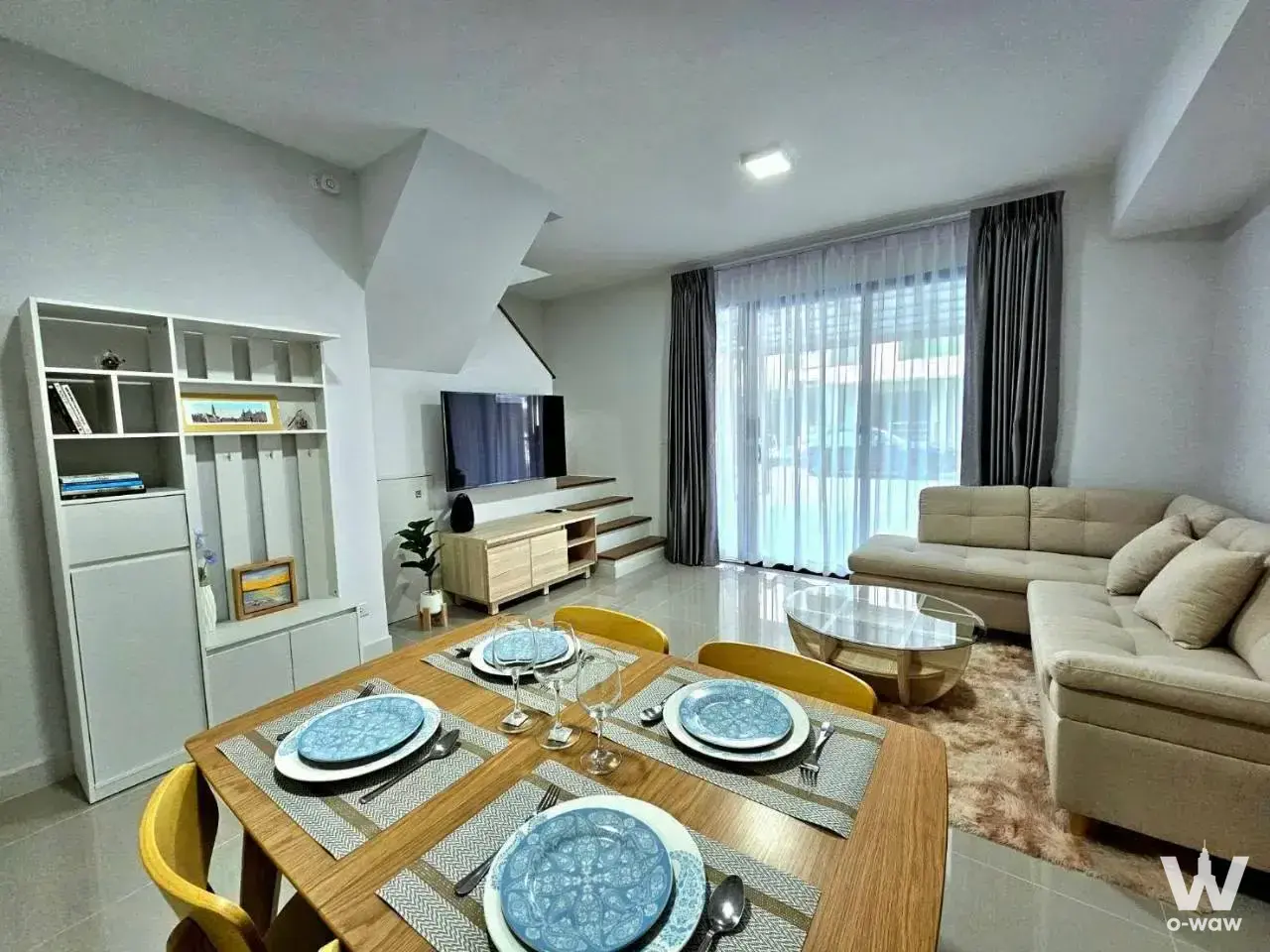 Open-plan dining room in a 3-bed rental at Pleno Sukhumvit-Bangna 2 with leather sofa and wood table