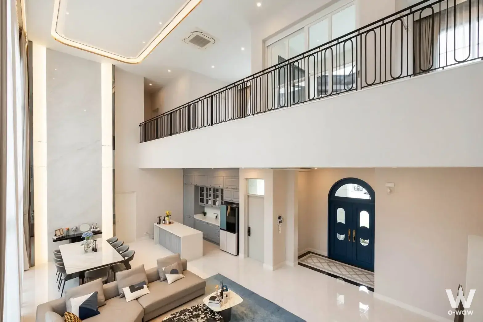 Double-height living room for sale in Narasiri Krungthep Kreetha with grey sofa and arched navy door