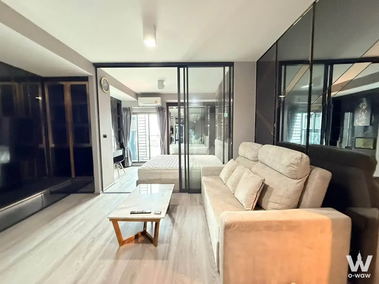 Open-plan studio with smoked glass walls and sliding partition separating the bedroom in an Ideo Sathon-Wongwian Yai rental