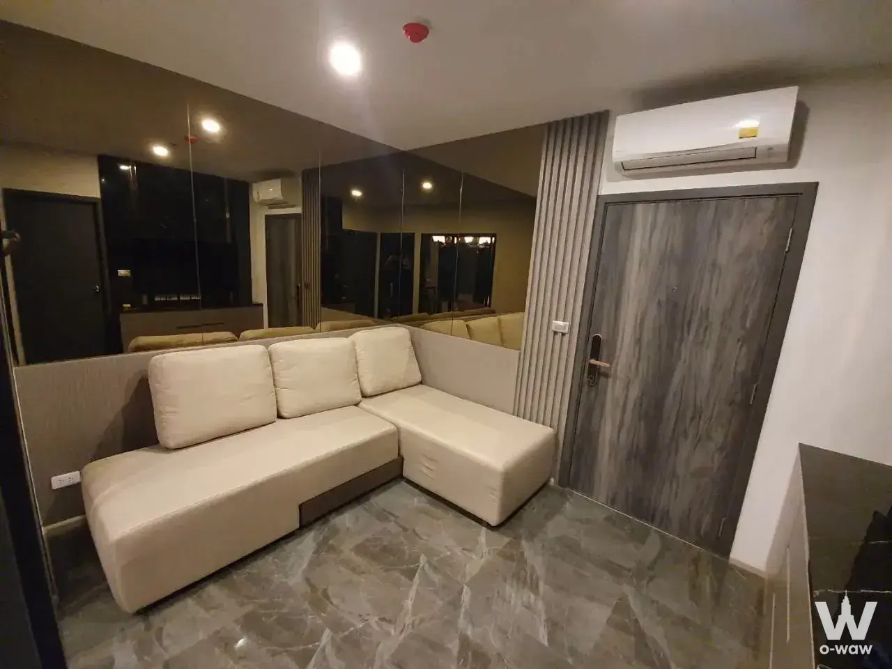 ELIO DEL NEST 1-bed condo living room featuring L-shaped sofa and mirrors