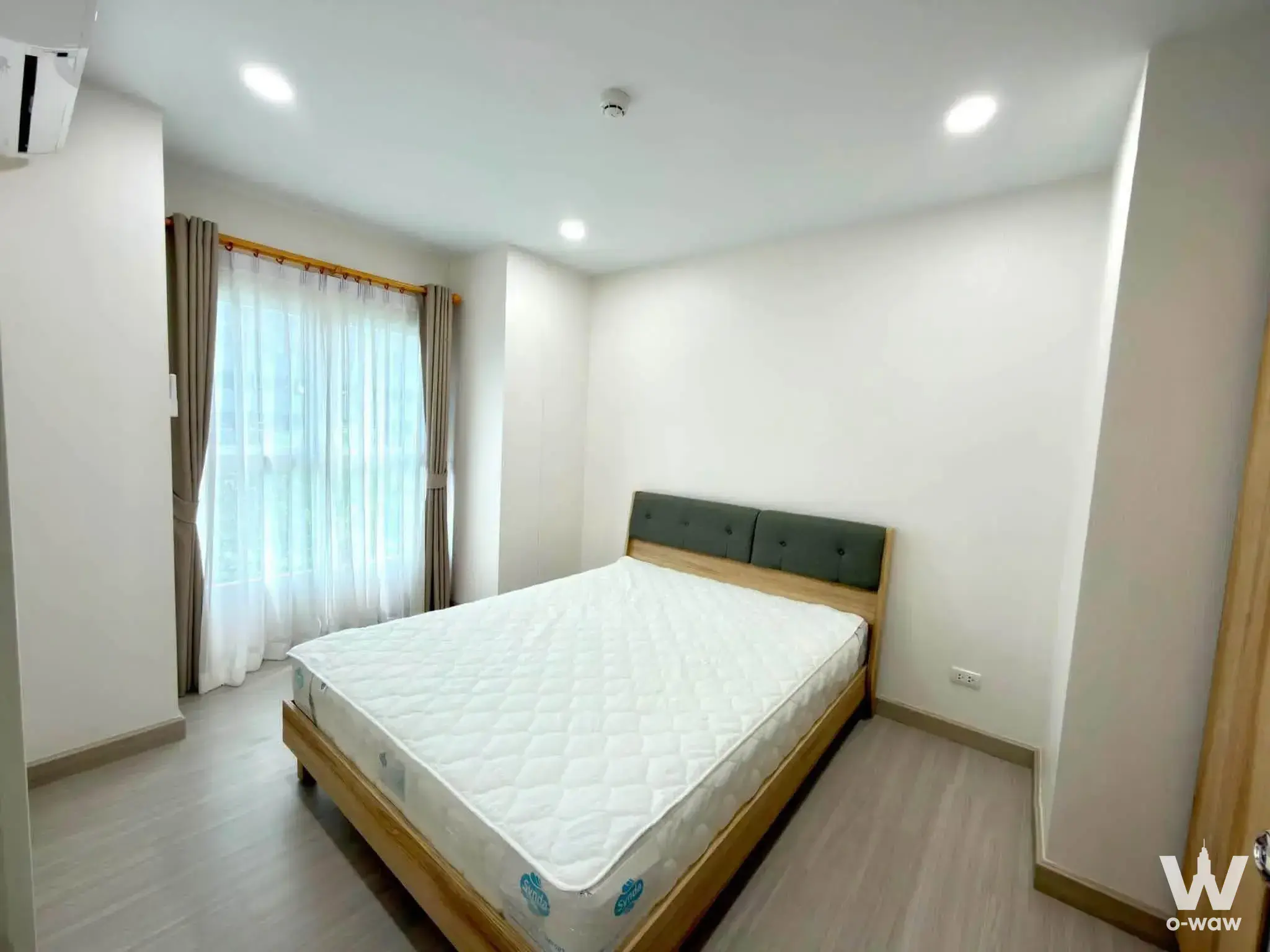 Modern 2-bed condo bedroom in Supalai City Resort Charan 91 with light-wood bed and dark-green tufted headboard