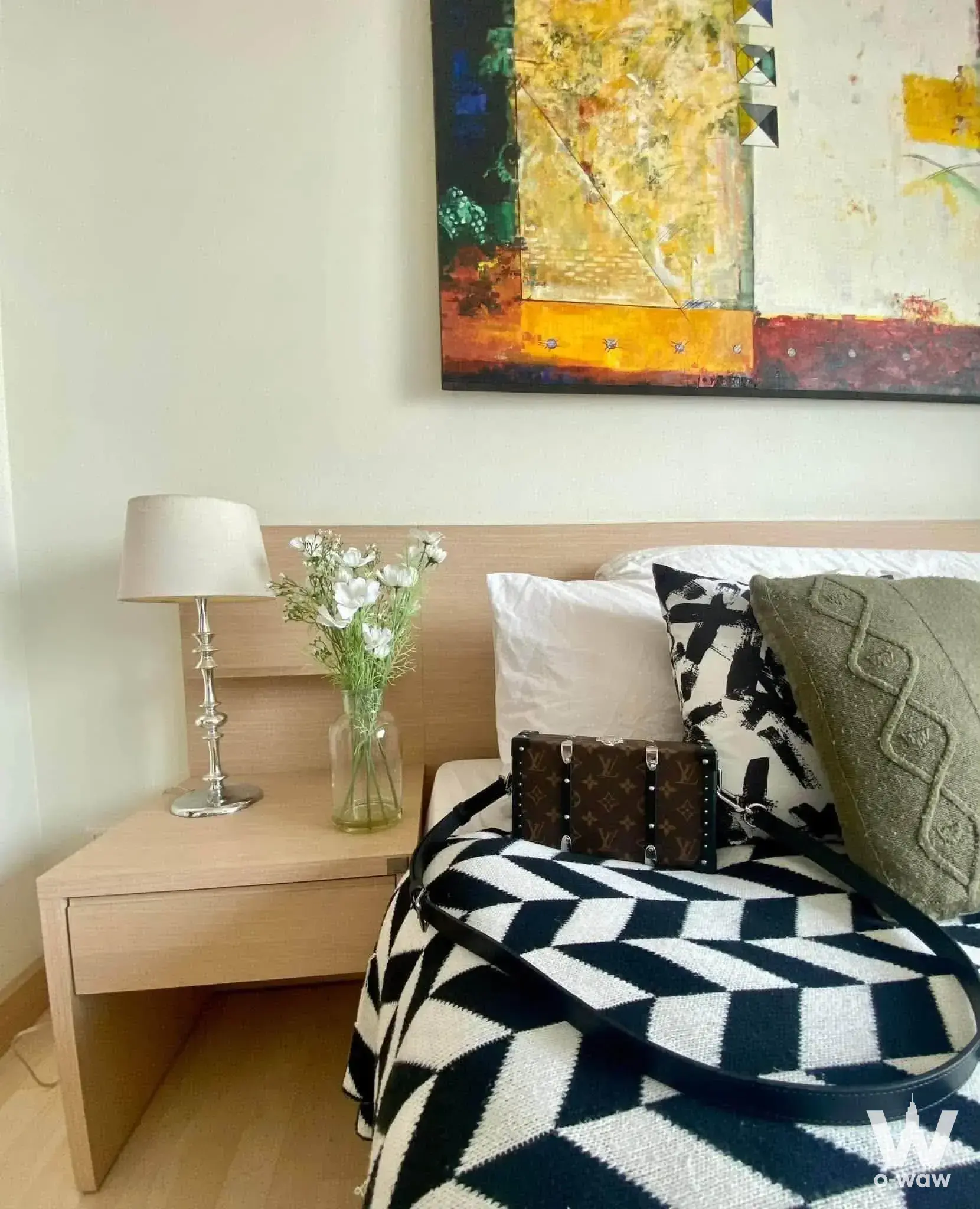 1-bed condo for rent in RHYTHM Ratchada bedroom with light-wood headboard, geometric throw blanket, and colorful abstract