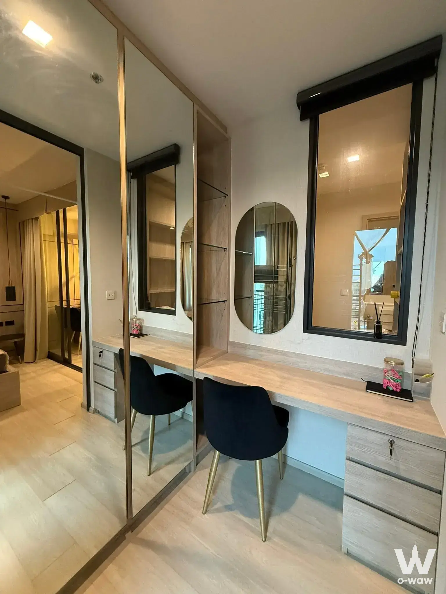 Vanity area in a Life One Wireless condo with mirrored wardrobe panels, velvet chairs, and wood shelving