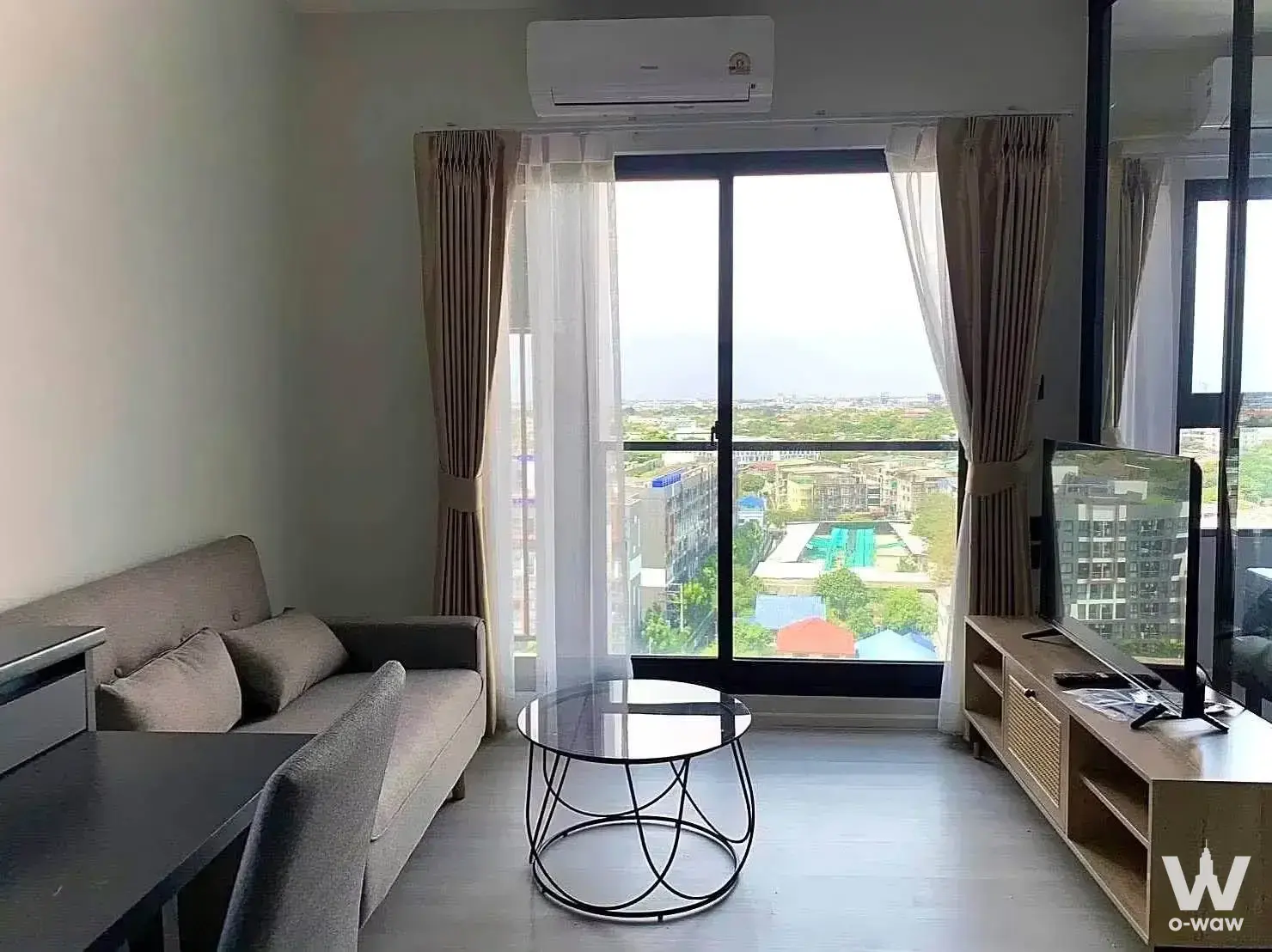 1-bed condo for sale in The Key MRT Phetkasem 48 with living room sofa, rattan TV console, and high-floor city view