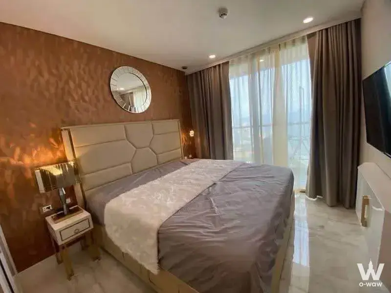 Master bedroom in a 1-bed condo for rent at Copacabana Coral Reef has a queen bed and copper wallpaper accent wall