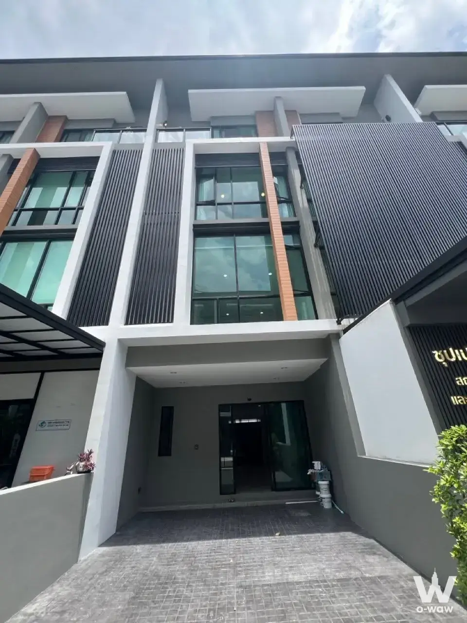 Modern townhouse facade with dark grey louvers and orange brick accents at Premium Place MIX Nonthaburi