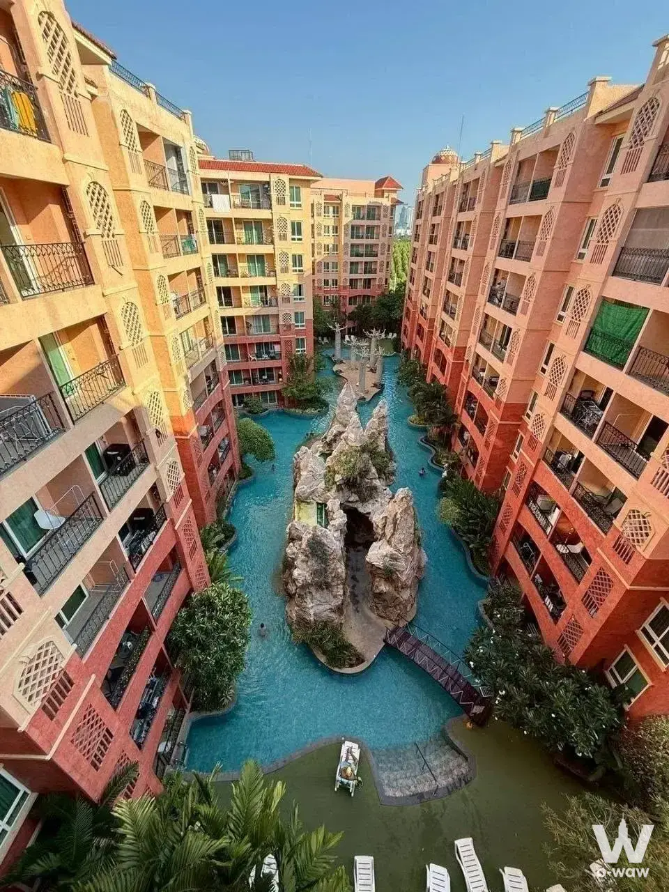 1-bed condo for sale in Seven Seas Condo Resort Jomtien overlooking a turquoise lagoon pool, terracotta facades, and