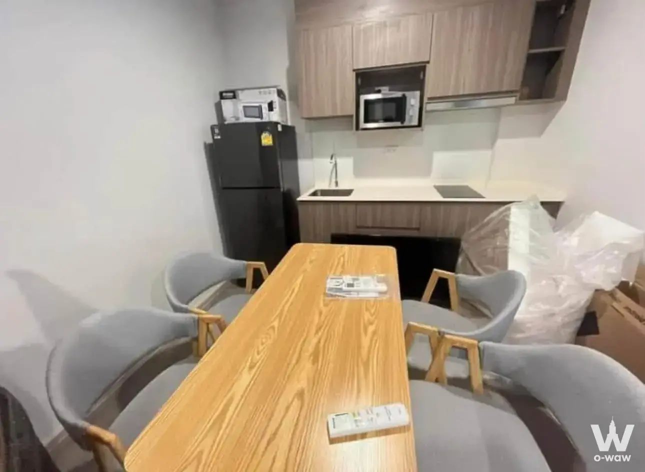Dining area with oak table and grey chairs next to kitchenette in a 2-bed condo for rent at The Parkland Charan-Pinklao