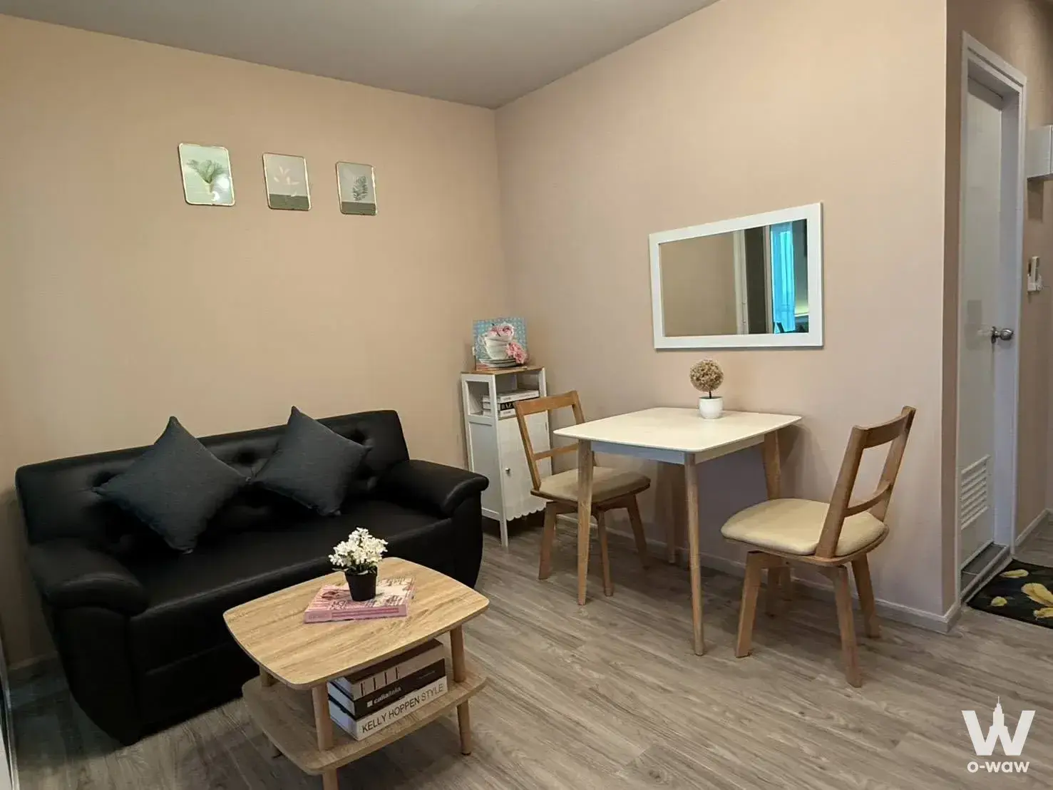 Compact living and dining area in Regent Home Bangna with a black leather sofa and white square table